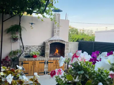a stone fireplace in a yard with flowers at Apart dom Janković in Sutomore
