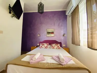 a bedroom with purple walls and a bed with two towels at Apart dom Janković in Sutomore