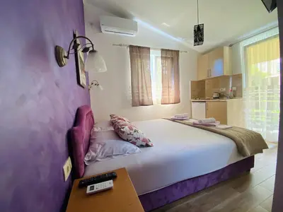 a bedroom with a large white bed and a table at Apart dom Janković in Sutomore
