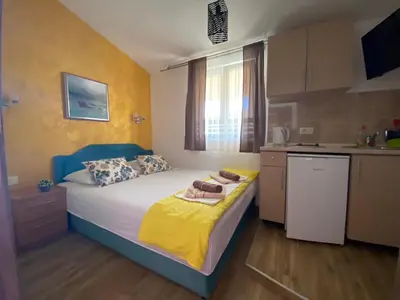 a small bedroom with a bed and a kitchen at Apart dom Janković in Sutomore