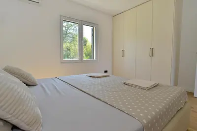 a white bedroom with a large bed and a window at Villa Jovanovic in Tivat