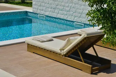 a pool with a lounge chair next to a swimming pool at Villa Jovanovic in Tivat