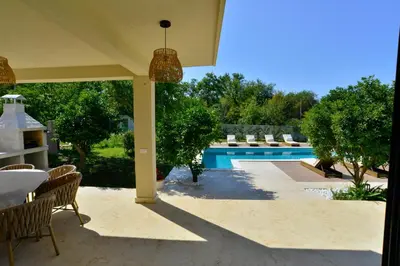 a patio with a table and chairs next to a pool at Villa Jovanovic in Tivat