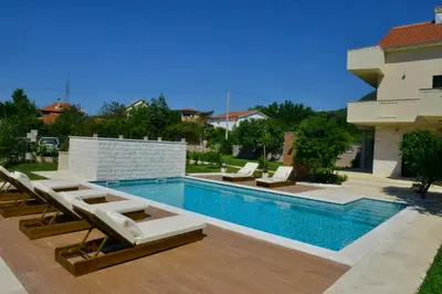 a swimming pool with loungers and chairs next to a building at Villa Jovanovic in Tivat
