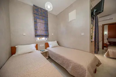 a bedroom with two beds and a tv on the wall at Kristal Apartmani in Čanj