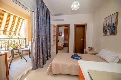 a bedroom with a bed and a table and a balcony at Kristal Apartmani in Čanj