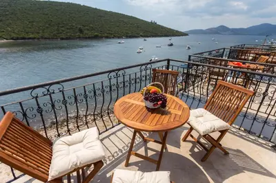 a table and chairs on a balcony with a view of the water at Villa SAN Apartments in Tivat