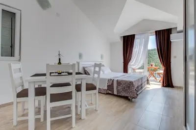 a white bedroom with a bed and a table and chairs at Villa SAN Apartments in Tivat