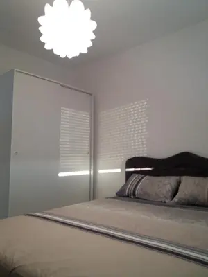 a white bedroom with a bed and a light at Holiday Home Duka's in Bar