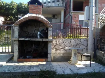 a stone fireplace with a bench in front of a building at Apartments Lux seaview in Bar