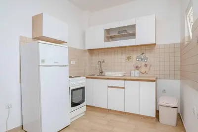 a kitchen with white cabinets and a white refrigerator at 1bd Modern Apt in Dobra Voda with Roof Access 