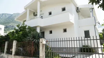 a white house with a fence in front of it at Apartmani Scepanovic in Sutomore