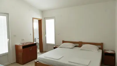 a bedroom with a bed and two windows at Apartmani Scepanovic in Sutomore