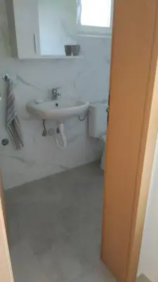 a white bathroom with a sink and a toilet at Apartmani Scepanovic in Sutomore