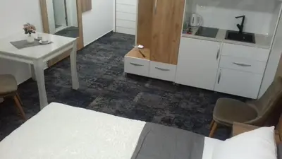 a room with a bed and a table and a kitchen at Tilia in Cetinje
