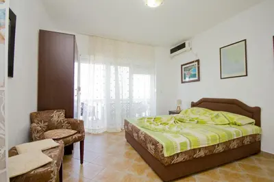 a bedroom with a bed and a chair and a window at Apartments Dora in Dobra Voda