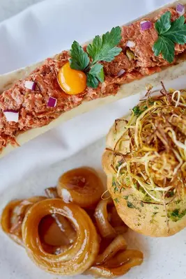 a plate of food with a sandwich and onion rings at Hotel Zeta in Budva