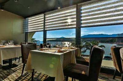 a restaurant with tables and chairs and a large window at Hotel Zeta in Budva