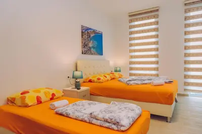 two beds in a room with orange sheets at Apartments Krstovic in Sutomore