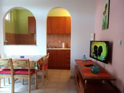a kitchen and dining room with a table and a television at Apartman Bošković in Budva