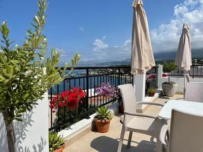 a balcony with a table and chairs and an umbrella at Apartments Tina in Utjeha