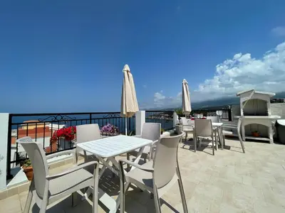 a patio with tables and chairs on a roof at Apartments Tina in Utjeha
