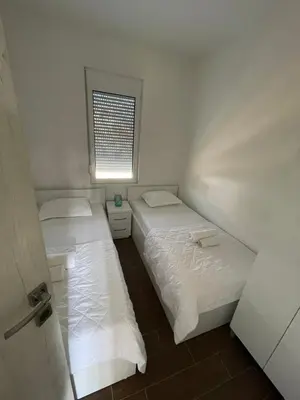 two beds in a small room with a window at Apartments Tina in Utjeha
