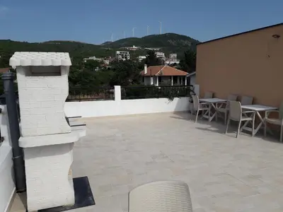 a patio with tables and chairs on a building at Apartments Tina in Utjeha