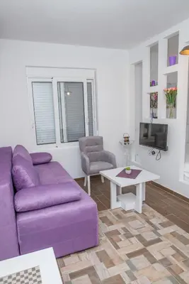 a living room with a purple couch and a table at Apartments Tina in Utjeha
