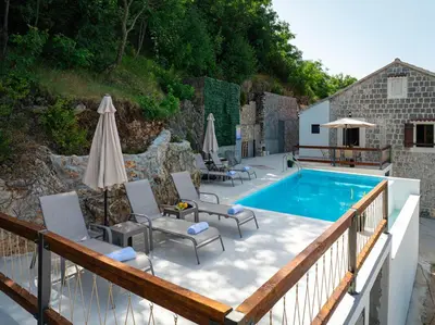 a patio with a pool and chairs and an umbrella at Villa Gorazda in Kotor