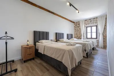 a bedroom with three beds and a brick wall at Villa Gorazda in Kotor
