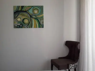 a chair sitting next to a painting on a wall at Apartman Nina in Bar