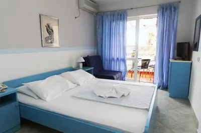 a blue and white bed in a room with a window at Hotel Obala in Budva