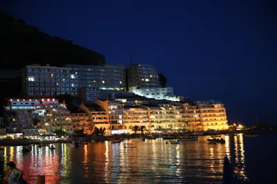a city lit up at night with buildings on the water at Hotel Obala in Budva
