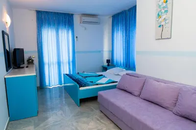 a living room with a purple couch and a bed at Hotel Obala in Budva
