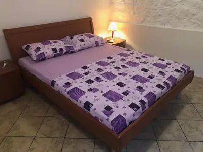 a bedroom with a bed with a purple bedspread and pillows at Apartmani Pavicevic in Podgorica