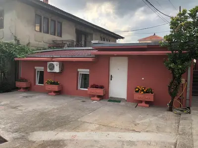 a red house with two windows and two flower boxes at Apartmani Pavicevic in Podgorica