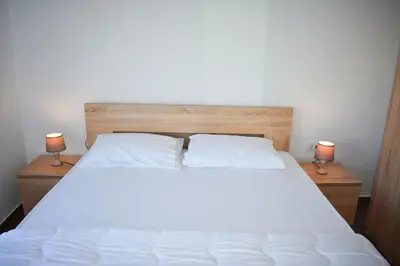 a bedroom with a white bed with two lamps at Apartment L'ideal in Ulcinj