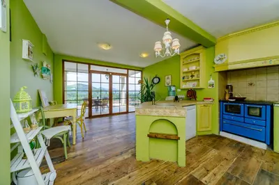 a kitchen with green walls and a dining room with a table at RUSTIC HOUSE LEKOVIĆ in Virpazar