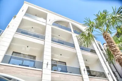 an apartment building with palm trees in front of it at Hotel Prova in Ulcinj