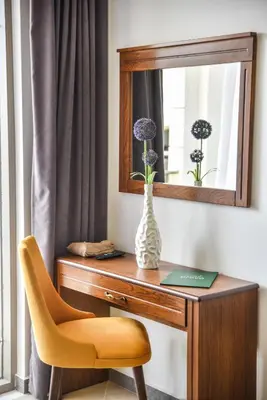 a desk with a vase and a mirror and a chair at Hotel Prova in Ulcinj