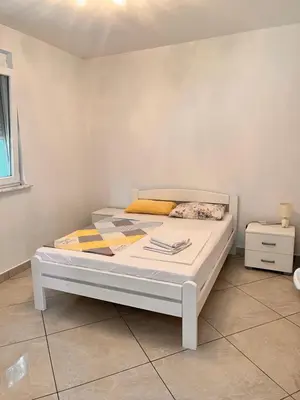 a white bed in a room with a white wall at Apartments Apartmani Bojana in Utjeha