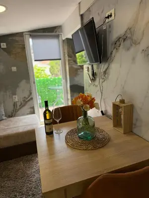 a wooden table with a vase of flowers and a television at Apartment viva Jelena in Budva