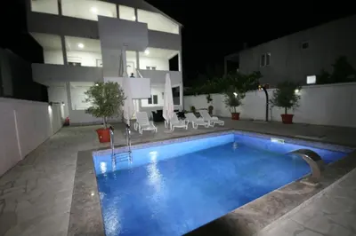 a swimming pool in front of a building at night at Apartmani Srdanovic in Tivat