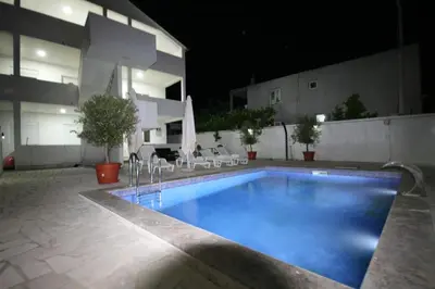 a swimming pool in front of a building at night at Apartmani Srdanovic in Tivat