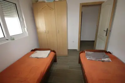 two beds sitting in a room with a window at Apartmani Srdanovic in Tivat