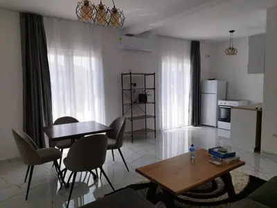 a living room with a table and chairs and a kitchen at Apartmani Srdanovic in Tivat