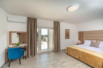 a bedroom with a bed and a desk with a blue chair at Mika's Seaview Apartments in Bar
