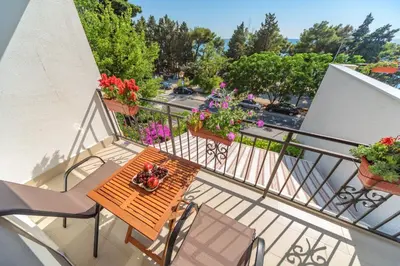 a balcony with a table and chairs and flowers at Mika's Seaview Apartments in Bar