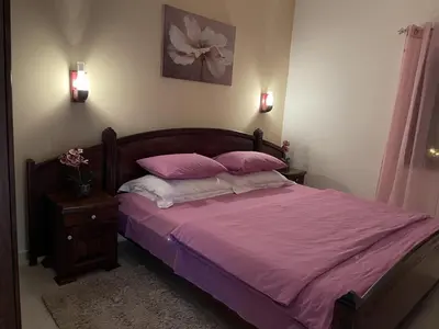a bedroom with a bed with pink sheets and pillows at Apartments Kalaja in Ulcinj